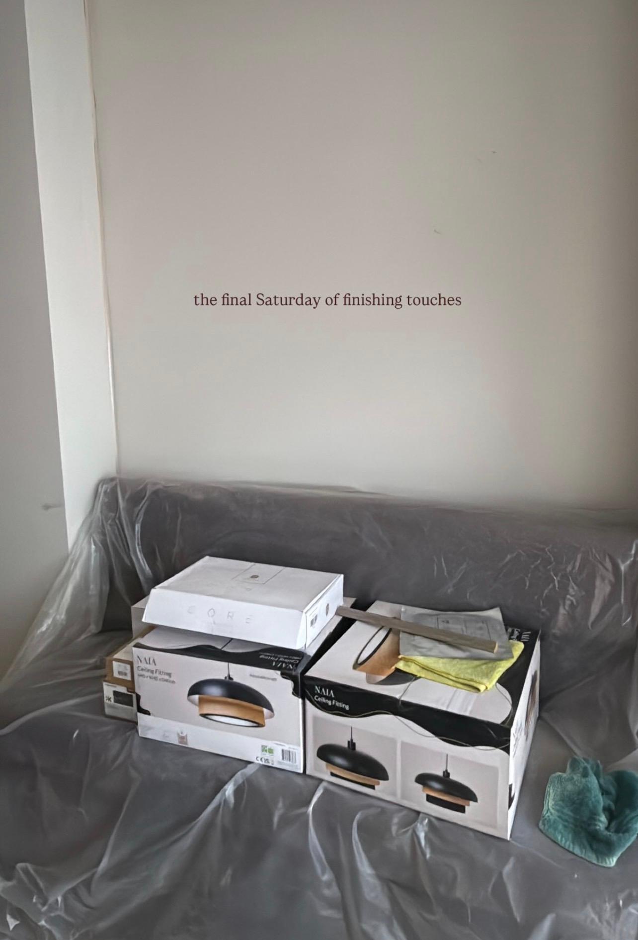 Light fitting boxes stacked on a dust-sheeted sofa during the last stretch of works