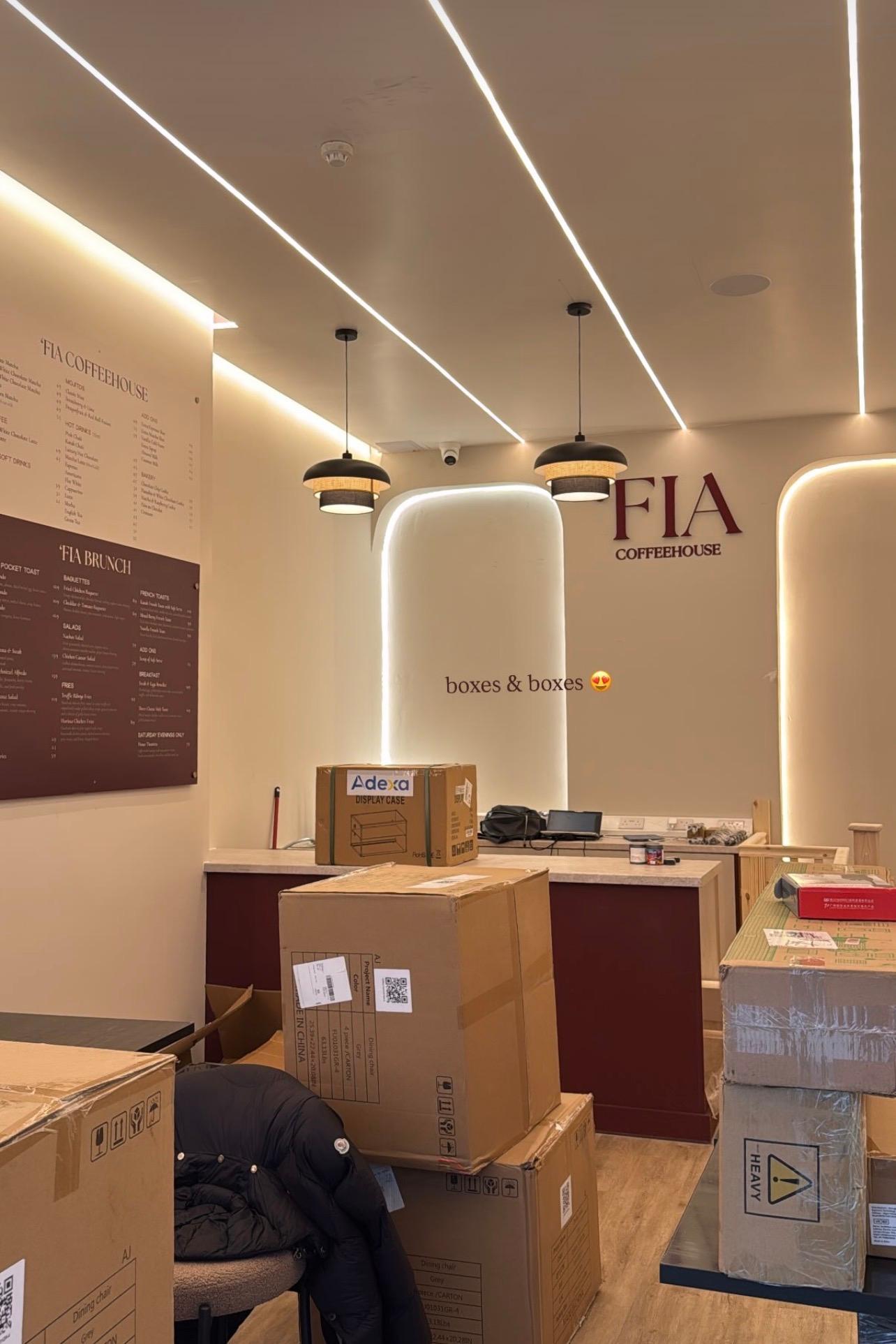 Menu boards up and furniture arriving, boxes still stacked around the room